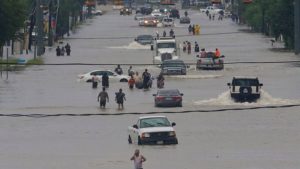 People walk through the flooded waters after Hurricane Harvey